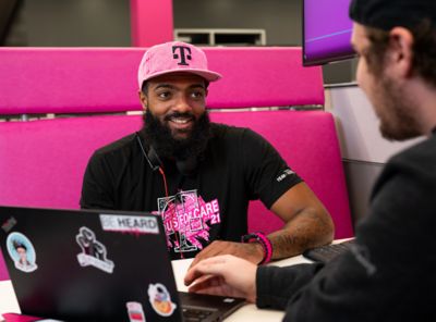 T-Mobile employee in a magenta hat, smiling at a customer.