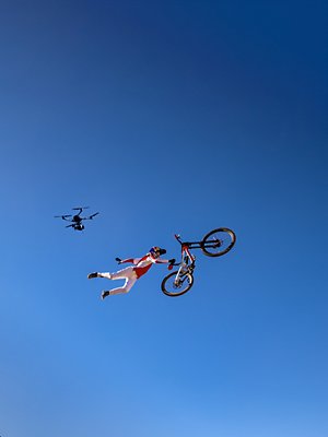 A drone capturing a biker doing a stunt midair.