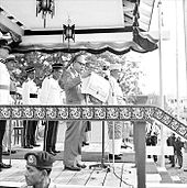 Ningkan holding papers containing the declaration, standing behind a microphone and in front of several guards on a podium