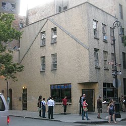 The Julius Bar Building, a gray stucco-faced building, as seen from across the street. There are people on the sidewalk in front of the bar.