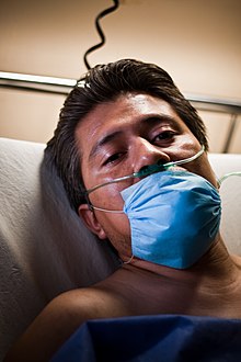 malade alité portant un masque respiratoire