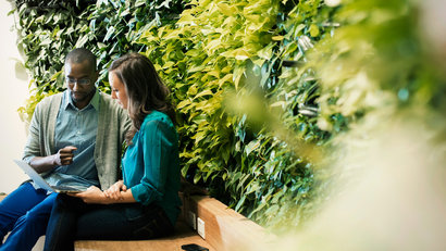 img-full-businessman-and-woman-sitting-in-front-of-green-plant-wall-using-laptop