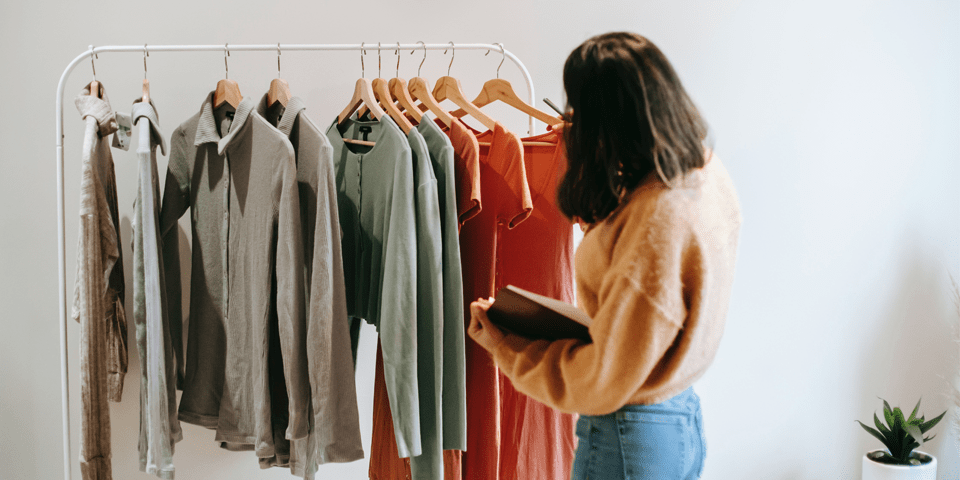 Butikkmedarbeider sjekker klær som henger på klesstativ