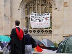 Graduating students pass an encampment protest over the Gaza conflict on the grounds of Cambridge University (Joe Giddens/ PA)