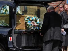 A funeral director places a floral tribute and photograph behind the coffin of Daniel Anjorin (Jonathan Brady/PA)