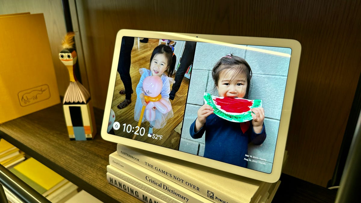 Google tablet on a bookshelf showing photos of kids