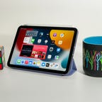 The new iPad Mini sits between a Rubik's cube and a mug for size comparison.