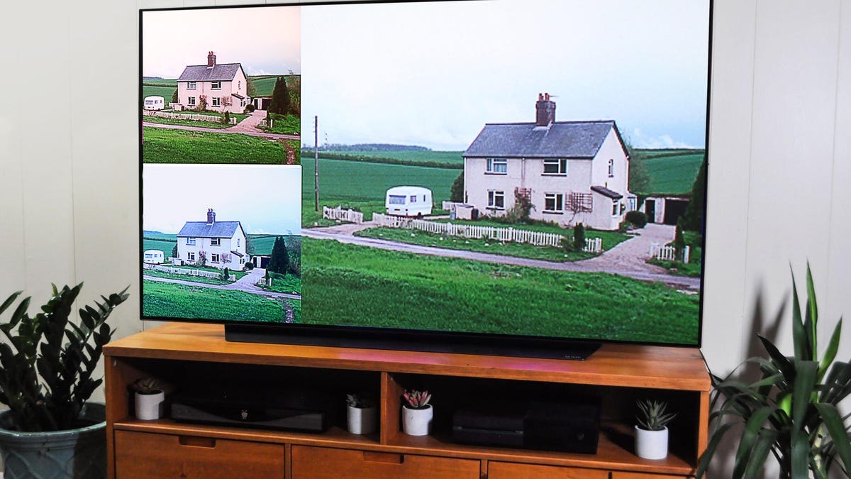 A TV on a wooden stand showing three images of the same house with different color temperatures.