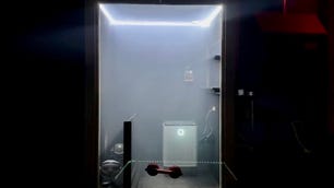 Our custom-built air purifier test chamber sits in the dark, the interior illuminated behind plexi-glass by white string lights. It's a sealed, closet-sized room that we fill with smoke to test each unit.