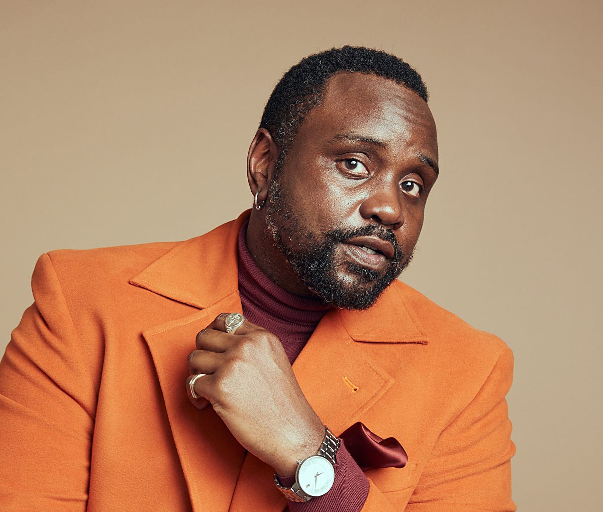 Brian Tyree Henry poses in a stylish orange suit.