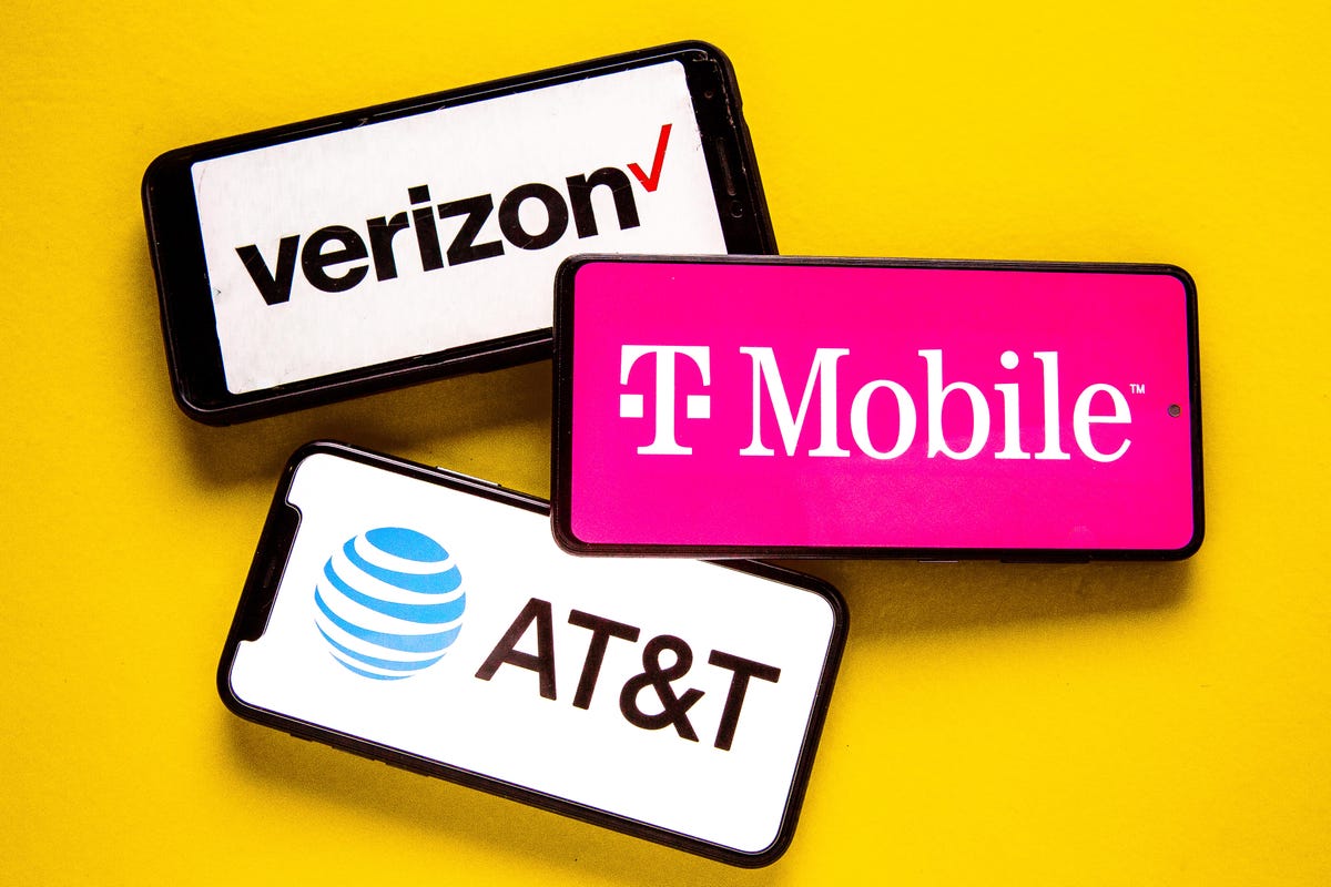 Three smartphones, each showing the name and logo of either Verizon, T-Mobile or AT&T