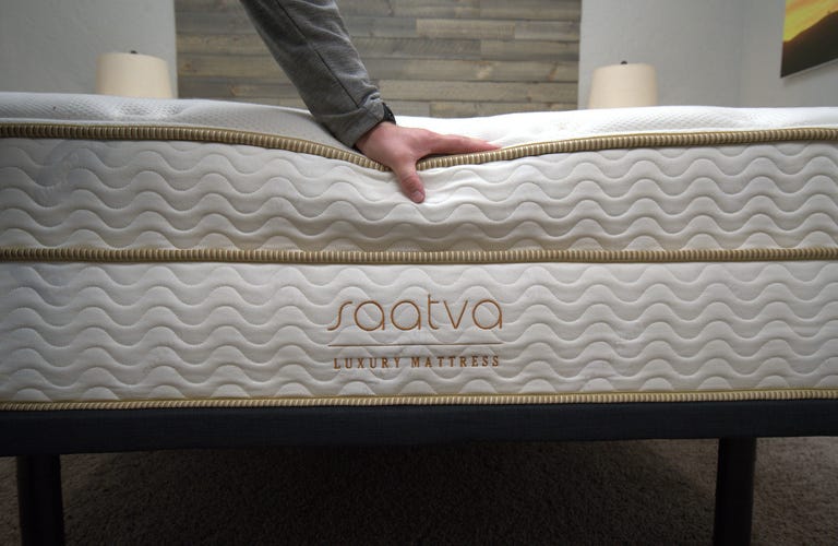 A person touching and feeling the top of the firm Saatva Classic mattress