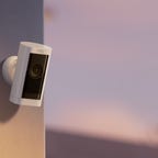 The wireless Ring Stick-Up Cam Pro sits perched on the corner of a home, keeping an eye on the exterior of the property.