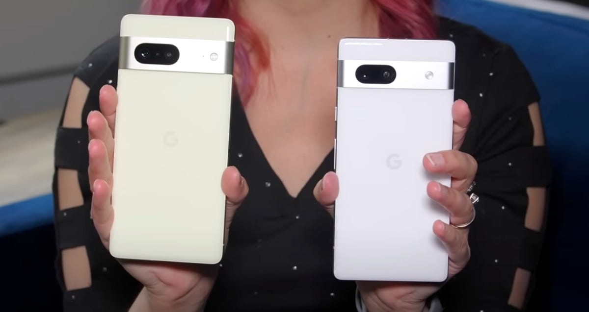 The Pixel 7 (left) and Pixel 7A (right) behind held up next to each other