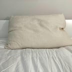 Avocado Green Pillow on a white bed.