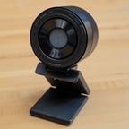 The Razer Kiyo Pro Ultra webcam with the mount extended standing on a light wood surface