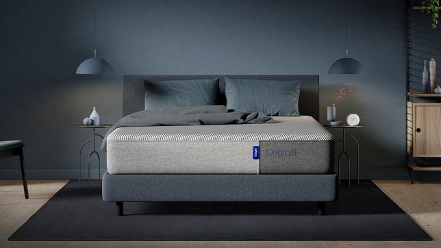 Casper Original mattress in a dimly lit room on top of a grey bed frame.