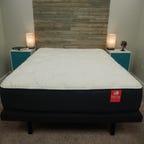 A Big Fig mattress on a grey bed frame in between two nightstands. 