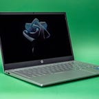 HP Pavilion 14 laptop open and facing to the right on a green background.