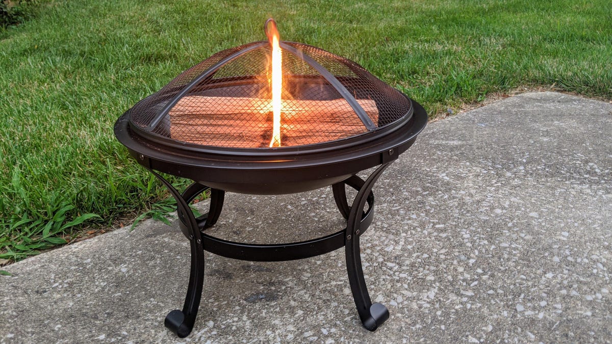 A small Kingso firepit outside with a single log burning inside.