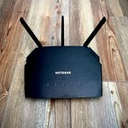 A Netgear r6700ax Wi Fi 6 router on a wooden surface