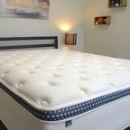 The WinkBed mattress on top of a metal bed frame in a bright room
