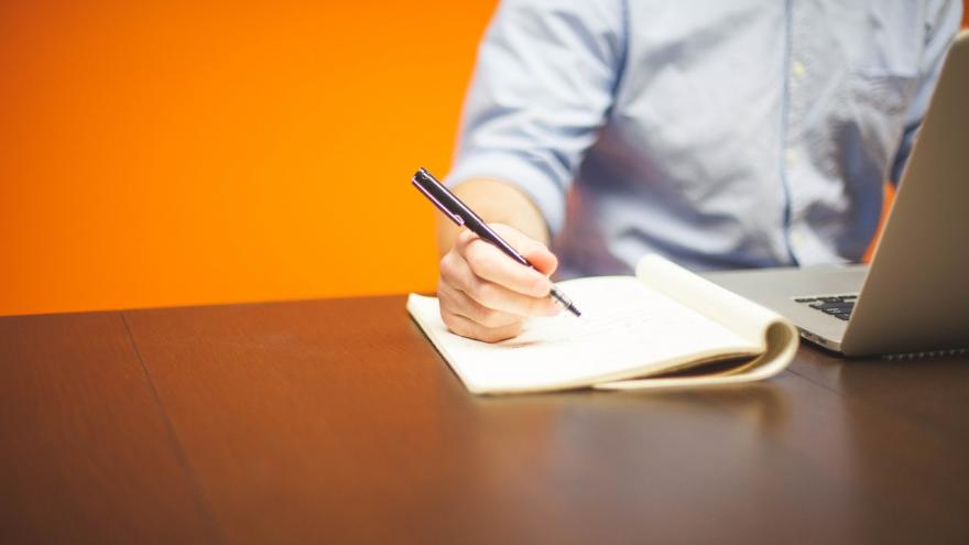 Imagen de mano de persona con bolígrafo escribiendo sobre una mesa