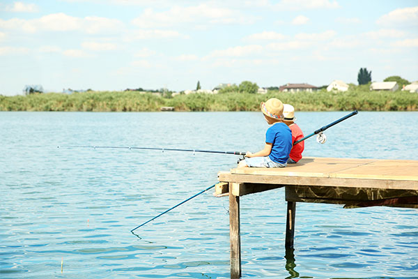 Two kids fishing off the end of a dock