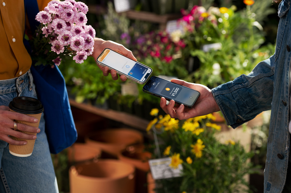 花を購入したお客様が自分のiPhoneを事業者のiPhoneにかざして決済を完了しているところ。