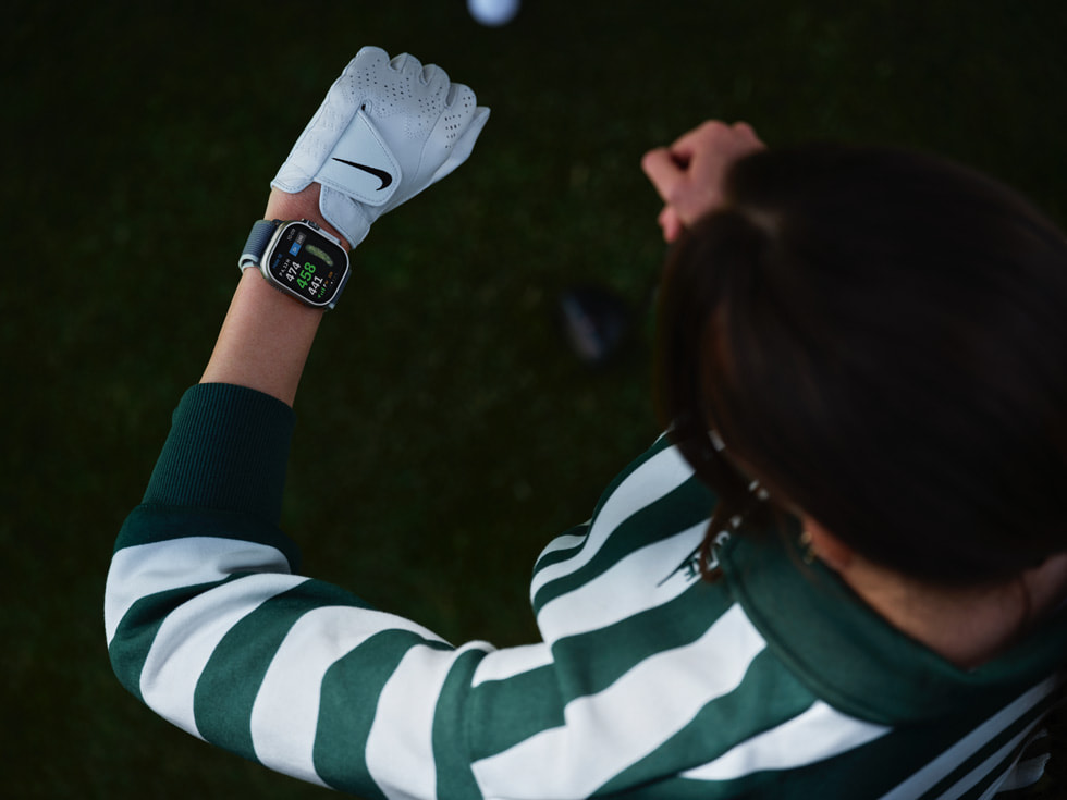 A golfer looking at their Apple Watch is shown from above.