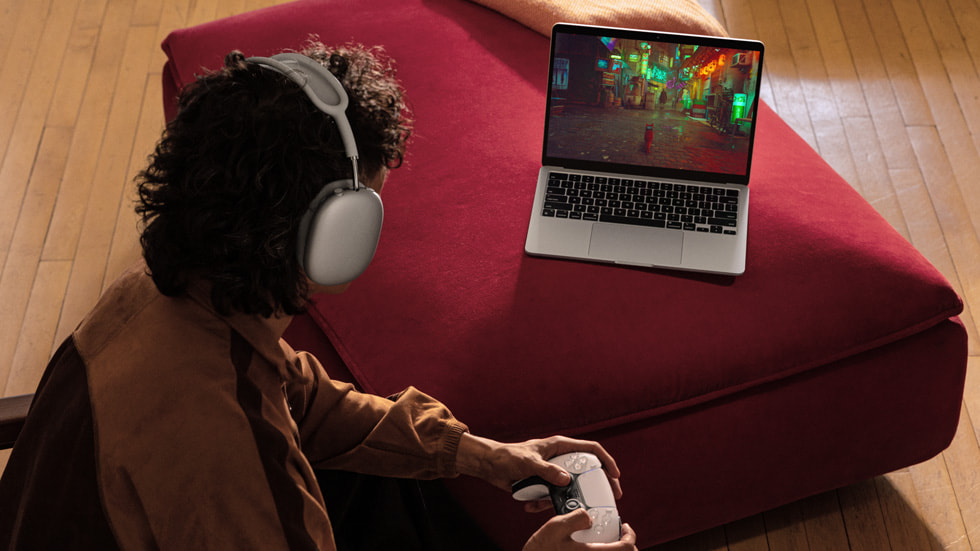 Una persona con indosso un paio di cuffie mentre gioca sul nuovo MacBook Air.