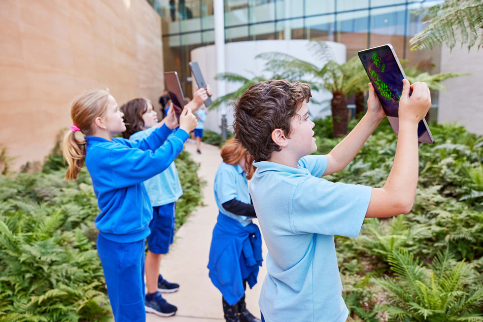 Students hold up iPad Pro to explore the world around them with the Deep Field app.