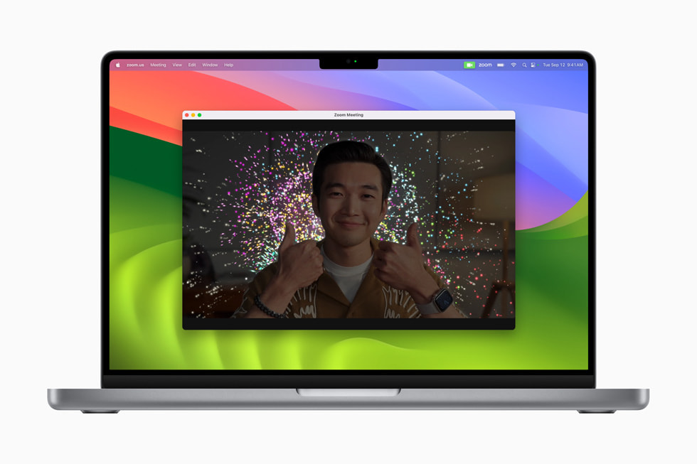 Una reunión de Zoom en un MacBook Pro con un efecto de fuegos artificiales detrás de la persona que presenta.