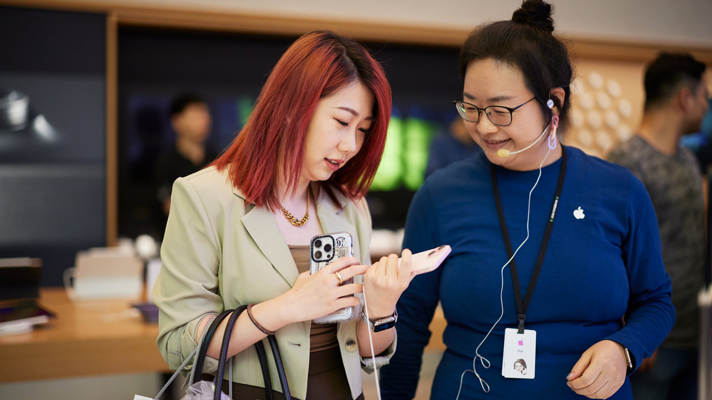Een klant houdt de roze iPhone 15 vast en praat met een medewerker bij Apple Nanjing East.
