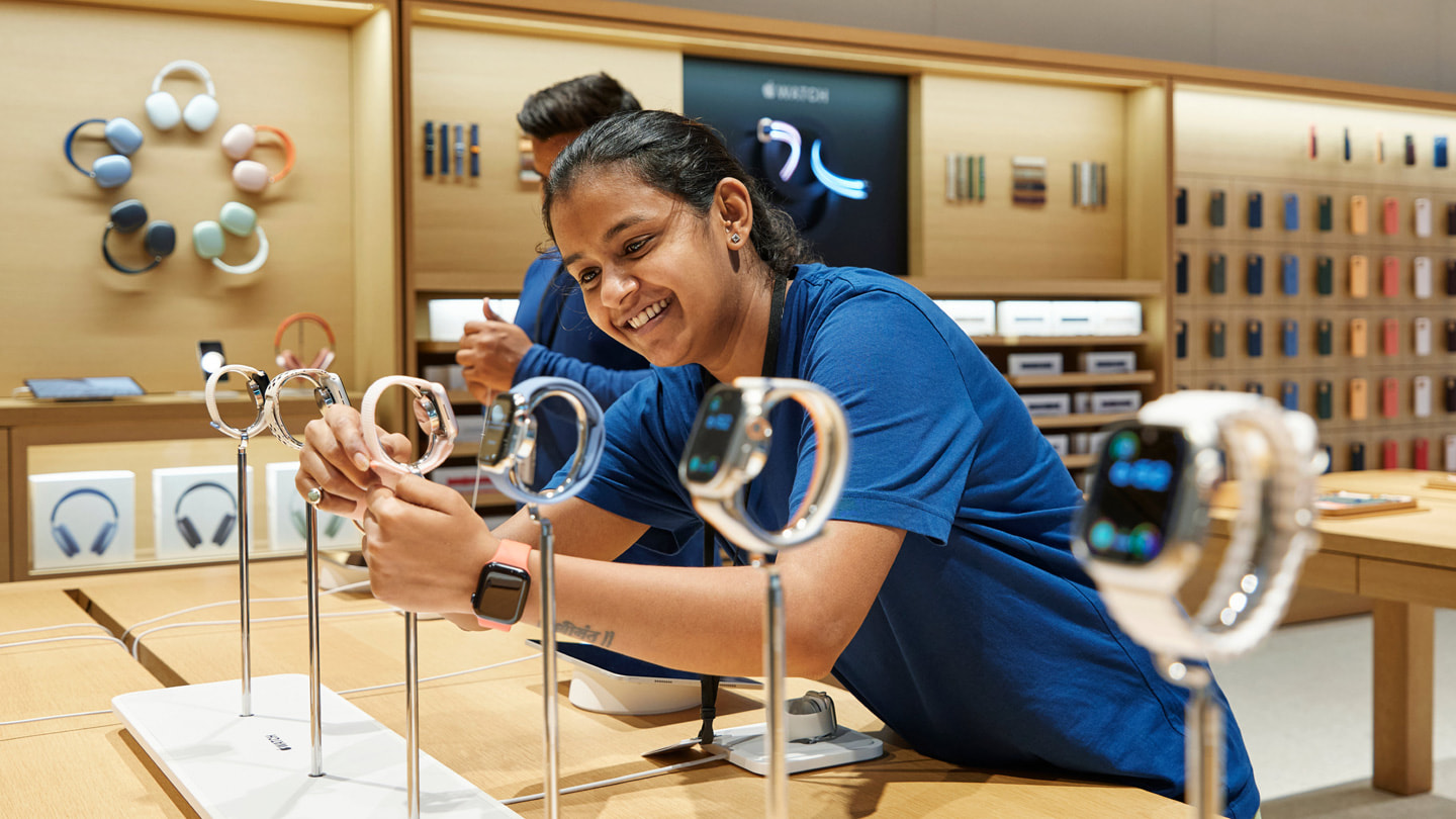 店内のディスプレイテーブルに陳列されている新しいApple Watch Series 9を調整する、Apple BKCのチームメンバー。