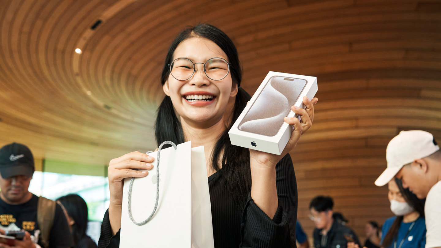 A customer showing off their new iPhone 15 Pro Max at Apple Central World in Bangkok.