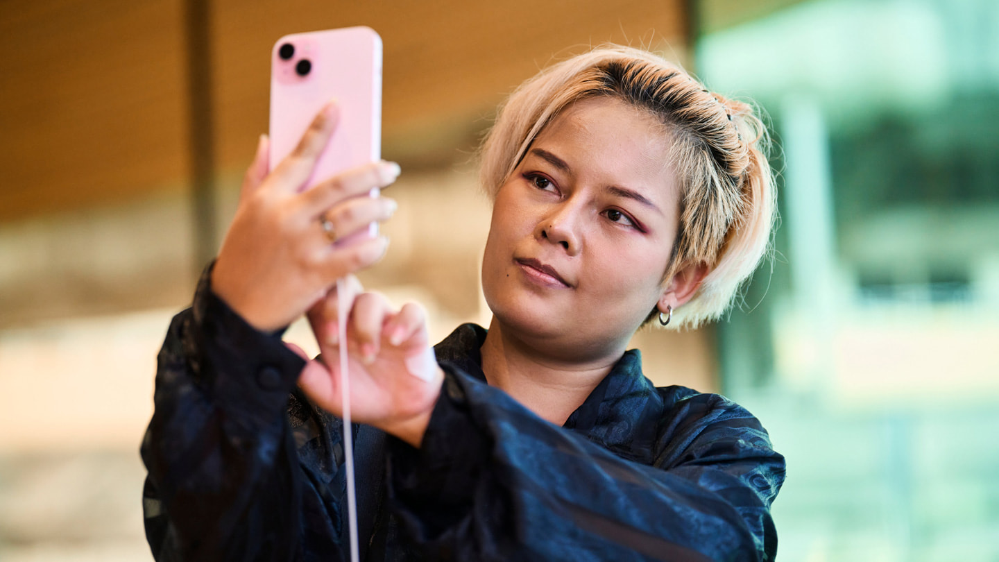 Een klant neemt een selfie met de roze iPhone 15 Plus bij Apple Central World in Bangkok.