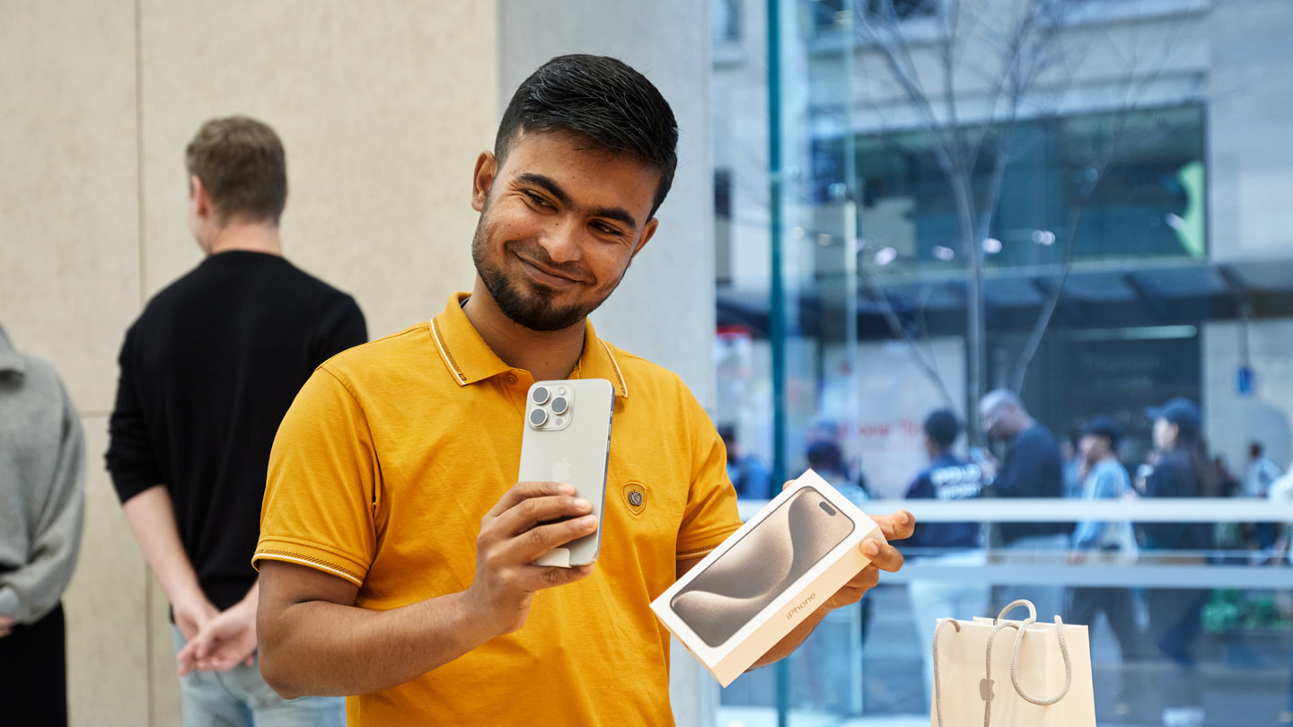 Een blije klant met in de hand een nieuwe iPhone 15 Pro in Apple Sydney, Australië.