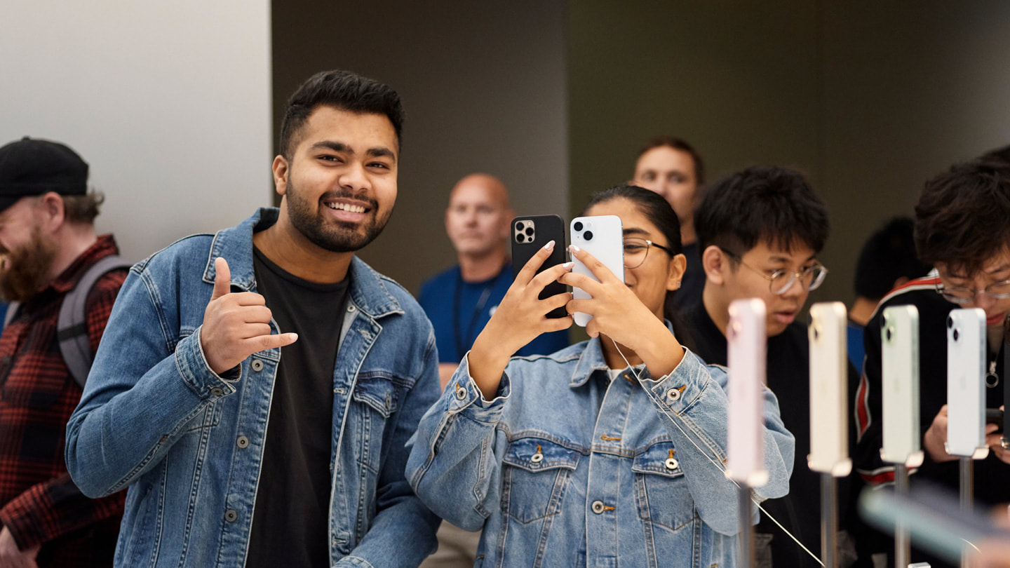 Twee klanten houden lachend twee iPhones omhoog in Apple Sydney, Australië.