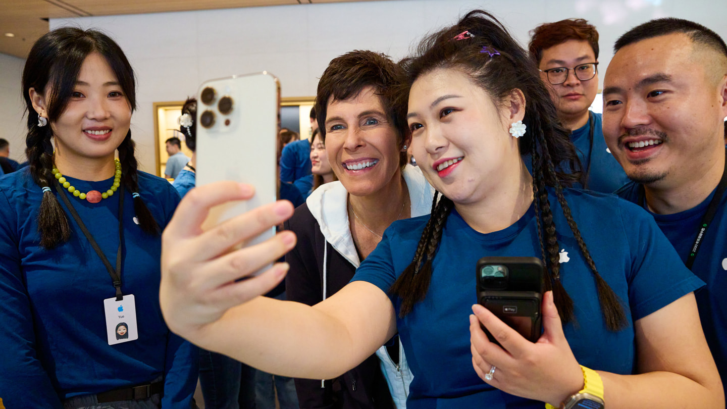 A team member takes a selfie with Deirdre O’Brien and others using the white iPhone 15 Pro.