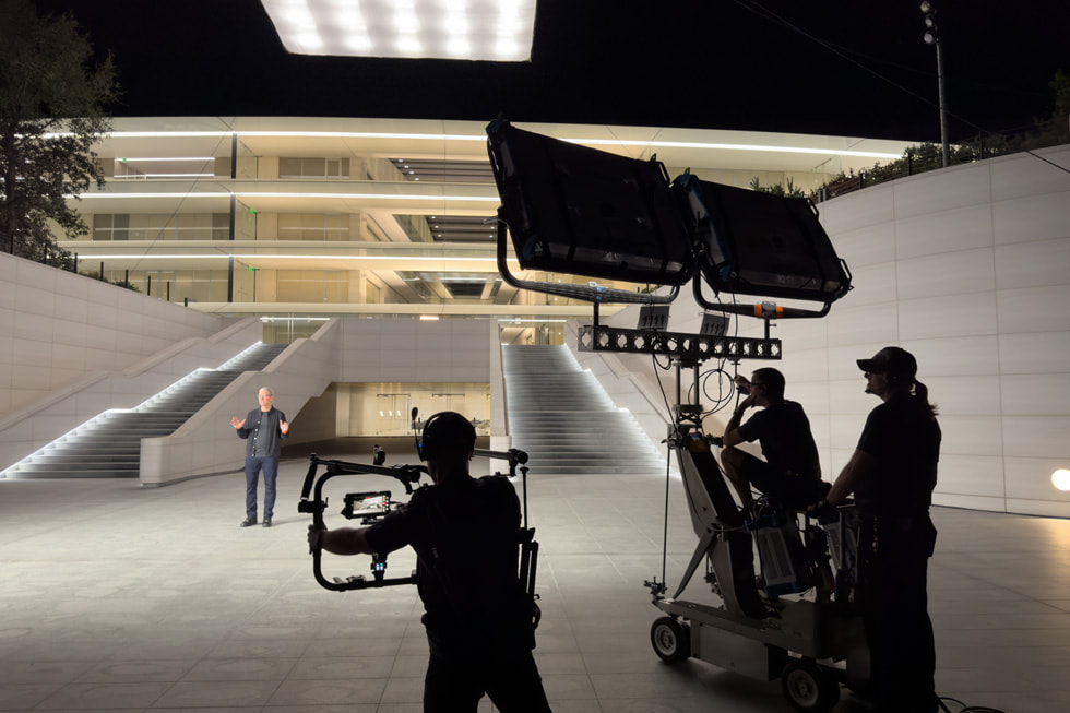 Des membres de l’équipe de tournage filment Tim Cook, qui est debout devant un escalier extérieur à Apple Park.