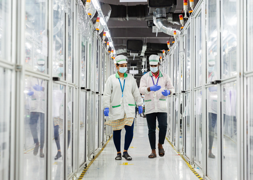 Two supply chain workers walk through a glass-encased corridor.