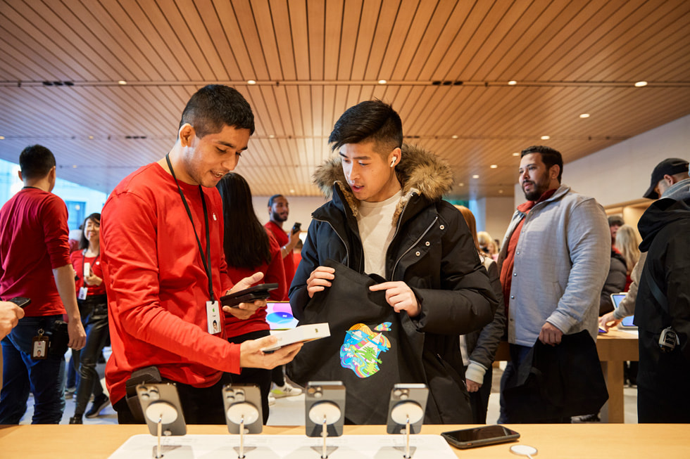 在加拿大溫哥華的 Apple Pacific Centre，一名團隊成員協助顧客購買 iPhone 14 Pro。