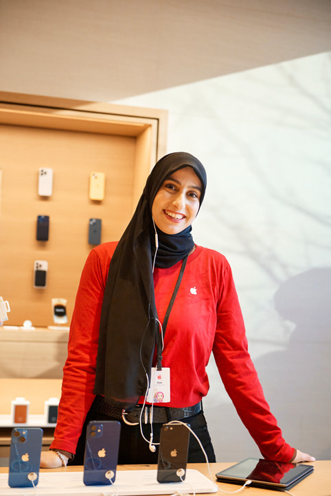Una integrante del equipo de Especialistas de Apple junto a una mesa de exposición del iPhone en la nueva tienda Apple Pacific Centre en Vancouver, Canadá.