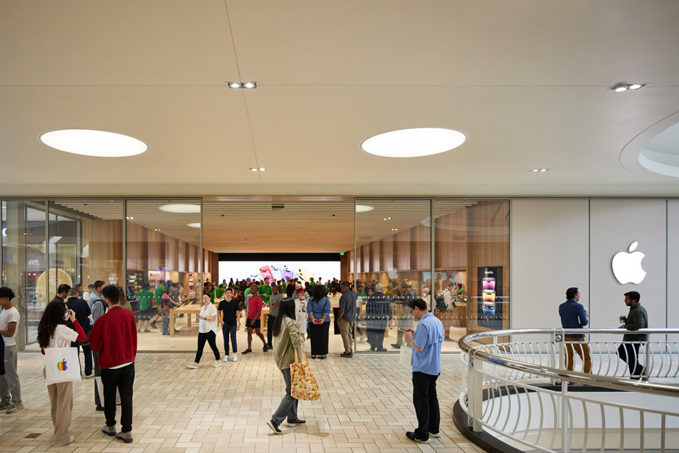 Butiksfacaden på Apple Tysons Corner vises inde i butikscenteret, hvor kunder er samlet og taler sammen.