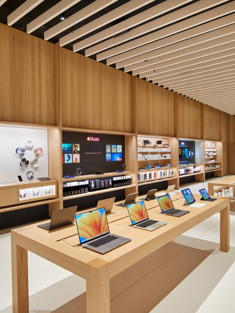Apple Tysons Corner 零售店的 Mac 展示台和產品展示牆照片。