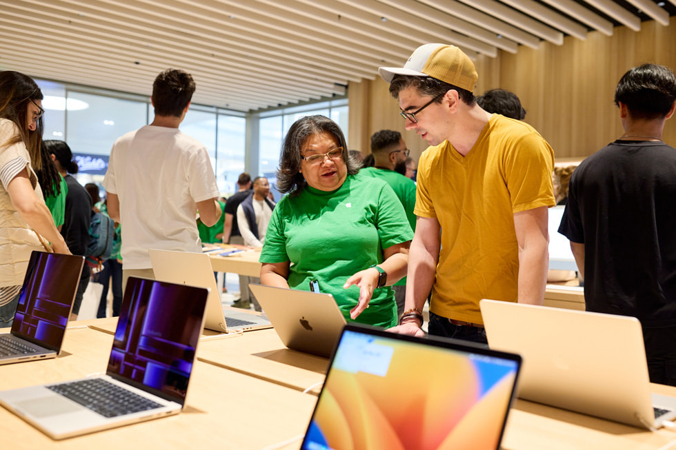 Ein Teammitglied zeigt einem Kunden die neuesten Mac Produkte.
