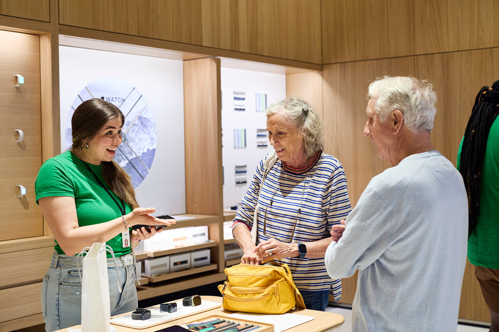 En medarbejder hjælper en kunde ved udstillingen af Apple Watch-enheder.