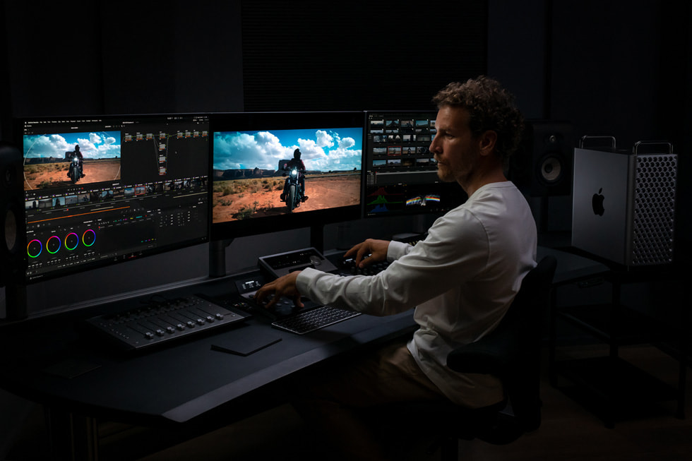 An Apple user working in DaVinci Resolve on Mac Pro is shown looking at an image on multiple displays.