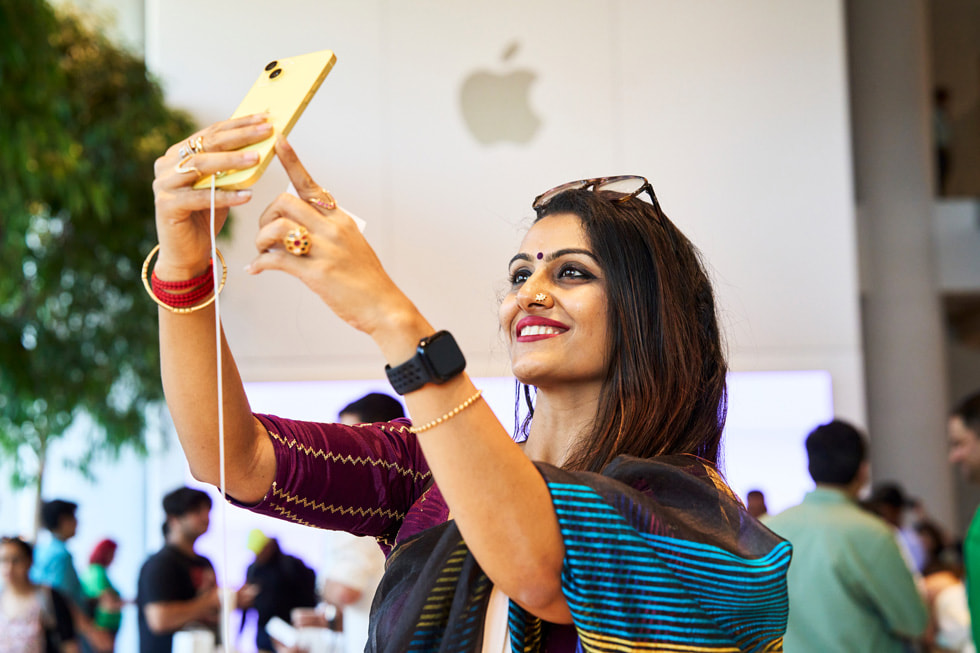 A customer takes a selfie with the yellow iPhone 14.